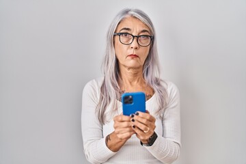 Poster - Middle age woman with grey hair using smartphone typing message relaxed with serious expression on face. simple and natural looking at the camera.