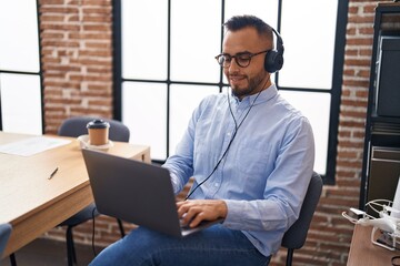 Wall Mural - Young hispanic man business worker using laptop and headphones at office