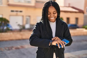 Poster - African american woman looking watch holding smartphone at park