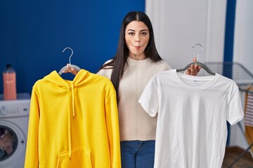 Poster - Young woman hanging clothes on racks making fish face with mouth and squinting eyes, crazy and comical.