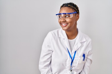 Poster - African american woman with braids wearing scientist robe looking away to side with smile on face, natural expression. laughing confident.