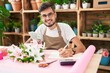 © Krakenimages.com - Young hispanic man florist counting dollars writing on notebook at flower shop