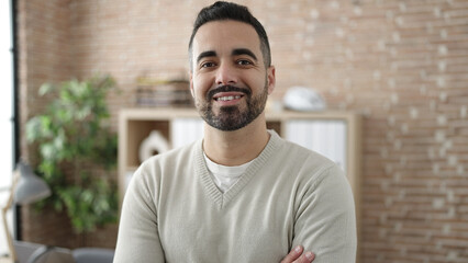 Canvas Print - Young hispanic man business worker smiling confident standing with arms crossed gesture at office