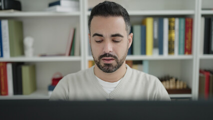 Sticker - Young hispanic man student using computer studying at library university