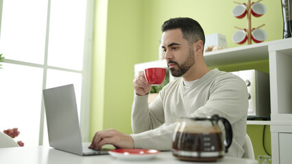 Sticker - Young hispanic man using laptop drinking coffee at home