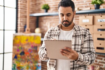 Sticker - Young hispanic man drawing on notebook at art studio