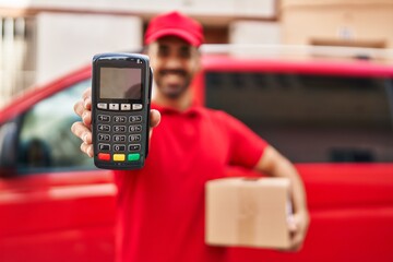 Sticker - Young hispanic man courier holding package and data phone at street