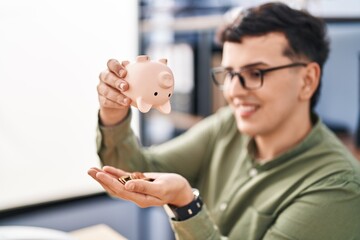 Canvas Print - Young non binary man business worker emptying piggy bank at office