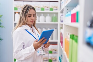 Wall Mural - Young blonde woman pharmacist using touchpad working at pharmacy