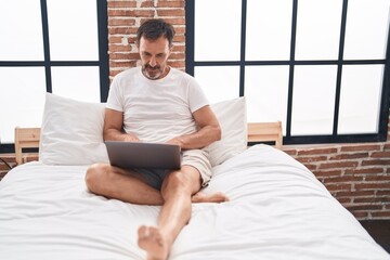 Poster - Middle age man using laptop sitting on bed at bedroom