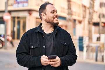 Wall Mural - Young hispanic man smiling confident using smartphone at street