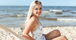 © rogerphoto - Happy blonde woman relaxing on a wooden deck chair at the ocean beach