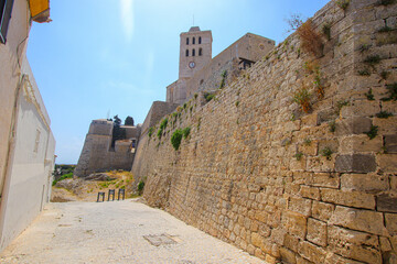 Wall Mural - Defensive wall surrounding the Castle of Eivissa in Dalt Vila, the old city center of Ibiza in the Balearic Islands, Spain - Bell tower of the Saint Mary Cathedral overlooking the Mediterranean Sea