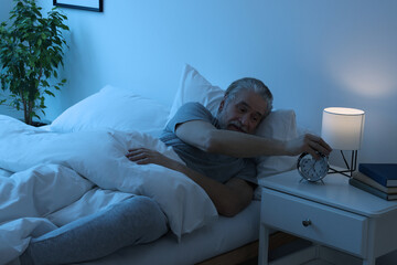 Sticker - Sleepy senior man turning off alarm clock in bedroom