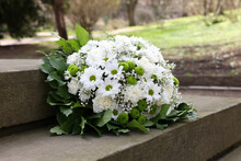 Funeral Wreath Of Flowers On Tombstone Outdoors