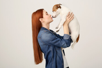 Sticker - Woman kissing cute Jack Russell Terrier dog on white background. Space for text