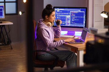 Young female programmer drinking coffee while working in office