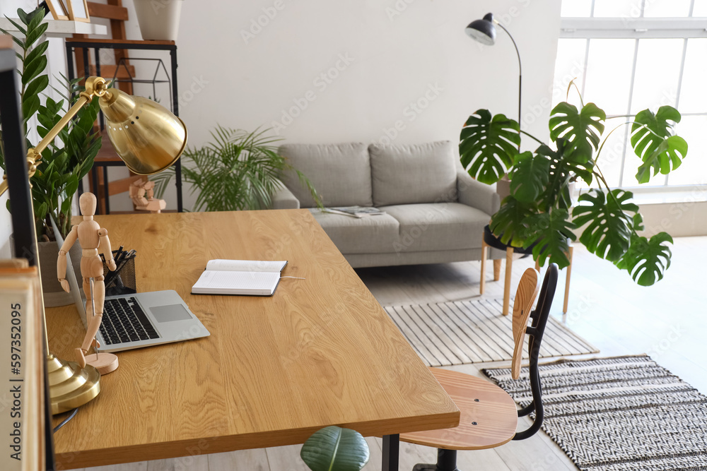 Interior of light office with sofa, workplace and Monstera houseplant
