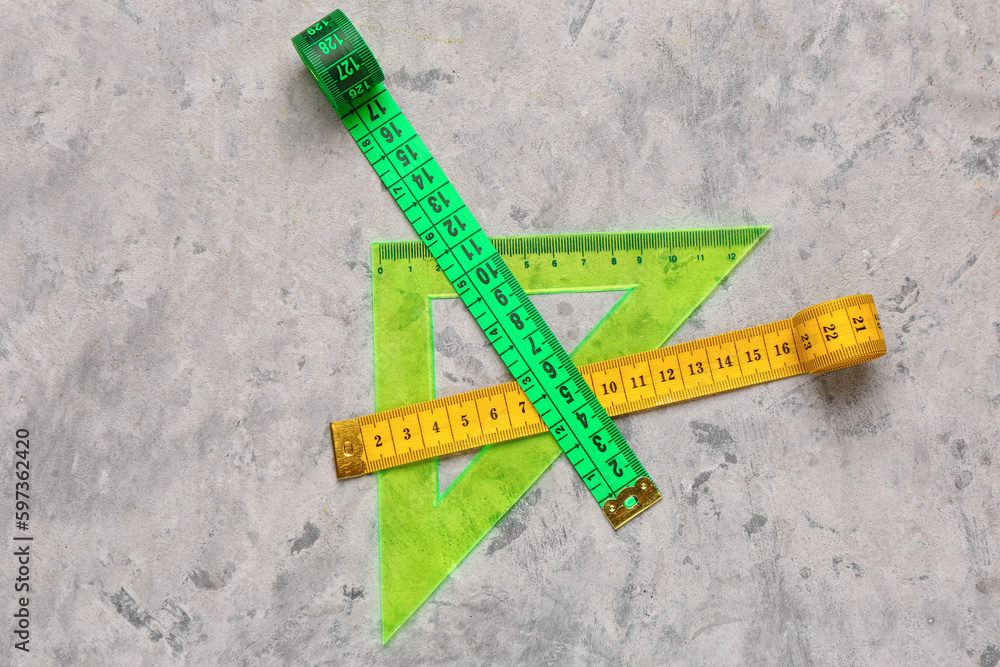 Colorful measuring tapes and triangle plastic ruler on grey grunge background