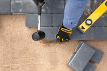 Laying Cement Pavement On A Walkway With A Rubber Hammer And Gloves On A Sand. House Improvement.