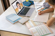 © Kostiantyn - Schoolboy sitting at table and writing in copybook on online lesson. Distance education concept