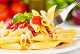 Fototapeta Kawa jest smaczna - Penne Rigatoni Rigate eating pasta on fork meal from Italy lunch with tomato sauce on a plate
