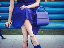Beautiful Woman With Blue Dress, Purple Purse, And Red High Heels On White Bench - AI Generated