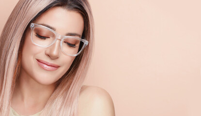 Wall Mural - Smiling beautiful woman in clear glasses against beige background. Clear vision and visual health concept