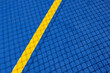 Sport field court background. Blue rubberized and granulated ground surface with yellow lines and tennis net shadow on ground. Top view