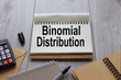 open notepad on wooden background different stationery the text- Binomial Distribution