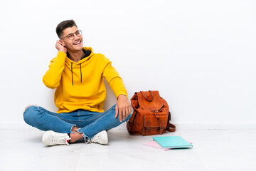 Wall Mural - Young student caucasian man sitting one the floor isolated on white background thinking an idea