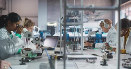 Leinwandbilder - Team of Multiethnic Science Students Conducting Electronics Experiments in a University Workshop. Diverse Young Classmates Using Microscopes, Working with Soldering Iron to Create a Circuit Board