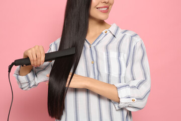 Sticker - Happy woman using hair iron on pink background, closeup