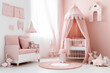 © Magryt - Pink colored baby nursery with cradle and play tent in scandinavian style. Baby girl bedroom. AI generated