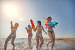 © luckybusiness - Group of cheerful friends having a water gun fight