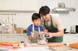 © tonefotografia - Happy young Asian father and kid are using a laptop computer to learn how to cooking food in their home kitchen.