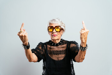 Wall Mural - Beautiful and elegant old influencer woman. Cool grandmother posing in studio wearing fashionable clothes. Happy senior lady celebrating and making party. Concept about seniority and lifestyle