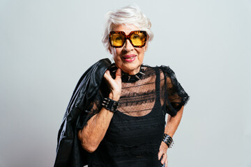 beautiful and elegant old influencer woman. cool grandmother posing in studio wearing fashionable cl