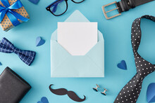 Happy Father's Day Concept. Top View Flat Lay Of Giftbox Bow Tie Glasses Wallet Necktie Mustache Belt Cufflinks And Hearts On Light Blue Background And Envelope With Card For Text In The Middle