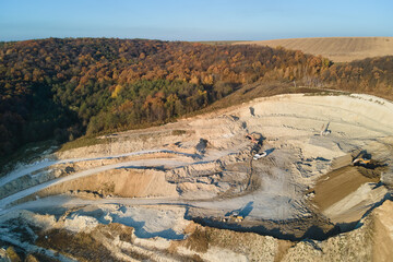 Wall Mural - Aerial view of open pit mine of sandstone materials for construction industry with excavators and dump trucks. Heavy equipment in mining and production of useful minerals concept