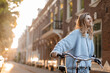 Leinwandbild Motiv 
Pretty young woman on bicycle in the city street, city transportation. Outdoor fashion portrait of elegant blonde curly lady riding her hipster retro bike in stylish blue sweater. 