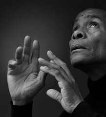 man praying to god with hands together Caribbean man praying with black background with people stock photos stock photo