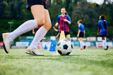 Fototapeta Sport - Close up of female player exercising with ball on soccer training at stadium.