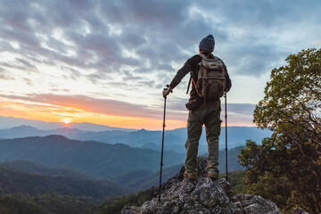 Wall Mural - hiker with backpack relaxing on top mountain landscape enjoy beautiful landscape view sunset.Hiker men's hiking living healthy active lifestyle.