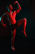 © SHOTPRIME STUDIO - Man bodybuilder athlete with bare torso fashion pose on black isolated background with colored light neon red and green. The concept of a healthy male body sport