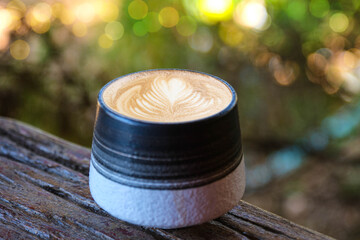 Hot latte coffee in a round mug on an old wooden table with warm light