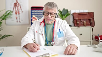 Poster - Middle age grey-haired man doctor having online medical consultation at clinic