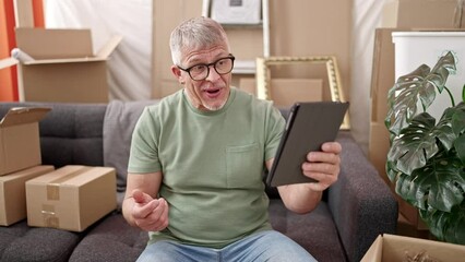 Sticker - Middle age grey-haired man having video call sitting on sofa at new home