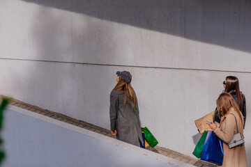 Wall Mural - A side view photo of three stylish girls walking into a shopping center