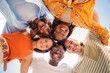 © Jose Calsina - Low angle view of a group of five multiracial teenagers smiling and looking down at camera outdoors. Young student people of diverse ethnic cultures embracing while standing in a circle,together. High